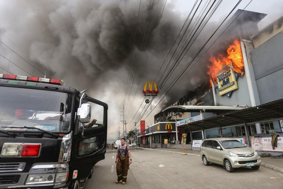 A firefighter stands in front of the NCCC Mall in Davao on the southern Philippine island of Mindanao. (Photo: MANMAN DEJETO via Getty Images)