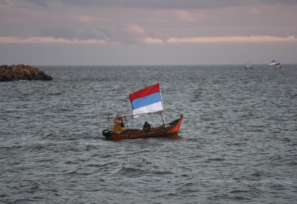 A boat flies a flag from Uruguay's ruling party Broad Front as it navigates off the coast before a closing campaign rally for presidential frontrunner Daniel Martinez in Montevideo, Uruguay, Wednesday, Oct. 23, 2019. Martinez, a former mayor of Uruguay's capital, will face off against the son of a former president in Uruguay's upcoming Oct. 27 general election. (AP Photo/Matilde Campodonico)