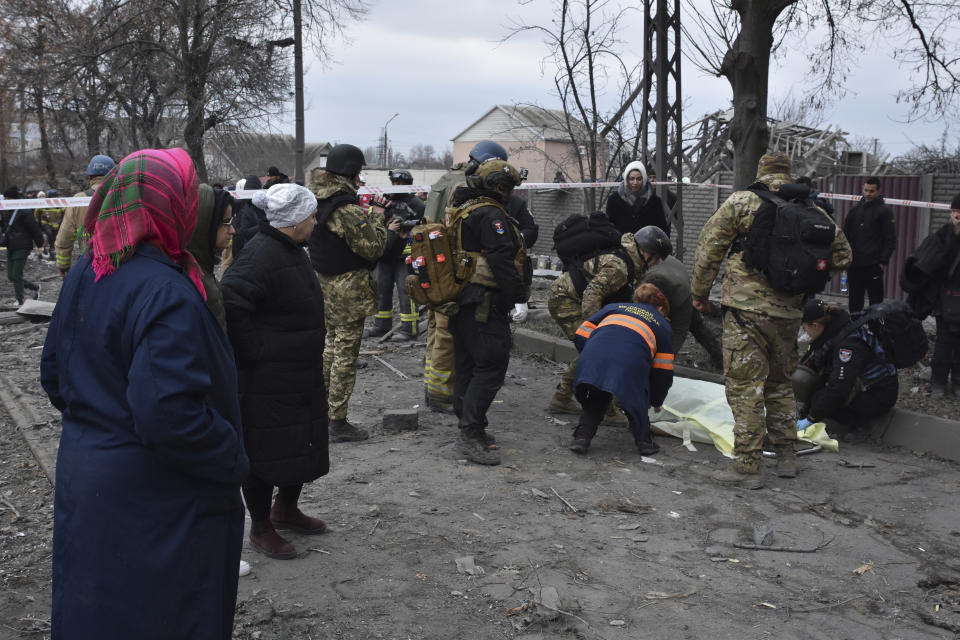 People react standing near the body of a resident killed in Russia' massive air attack in Zaporizhzhia, Ukraine, Friday, Dec. 29, 2023. Russia launched missiles as well as drones against Ukrainian targets during the night Ukraine President Volodymyr Zelenskyy said Friday, killing a number of civilians in what appeared to be one of the biggest aerial barrages of the 22-month war. (AP Photo/Andriy Andriyenko)