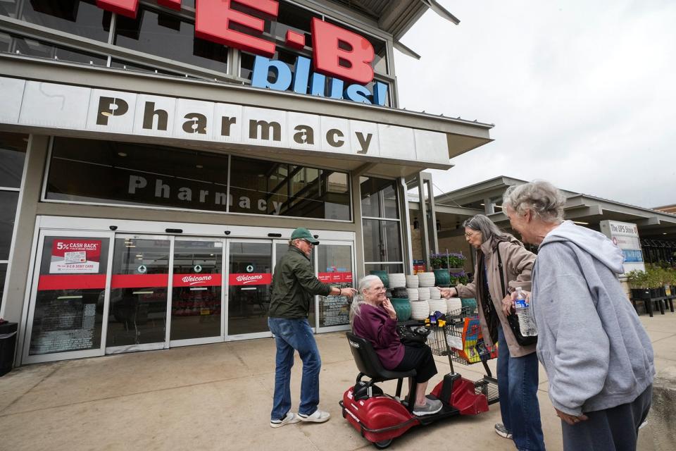 Senior Access driver Bill Raymond, left, and Marilyn Horndt, right, help Barbara Kullenberg, middle, into her motorized shopping cart as Molly Kam, far right, watches.