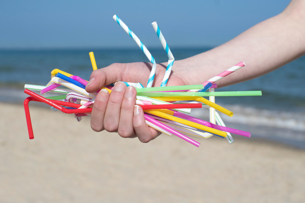 Close Up Of Hand Holding Plastic Straws Polluting Beach