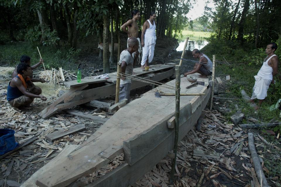 In this Aug. 6, 2018 photo, monks, in white, instruct carpenters making boats at a Vaishnavite Hindu monastery in Majuli, in the northeastern Indian state of Assam. Majuli is said to be one of the largest river islands in the world, surrounded by the fast-moving waters of the massive, though braided, Brahmaputra river. The island, known as the cultural capital of Assam with its Hindu religious Vaishnavite monasteries, floods every year with water ripping its banks, inundating homes, claiming lives and lands. (AP Photo/Anupam Nath)