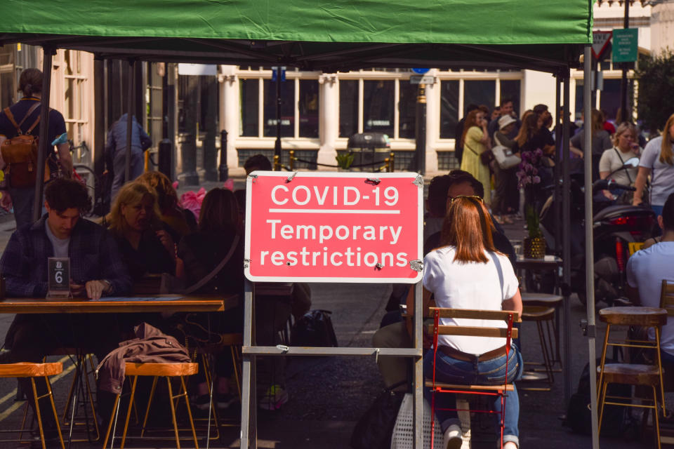 <p>LONDON, UNITED KINGDOM - 2021/09/05: A 'COVID-19 Temporary Restrictions' sign is seen outside busy restaurants and cafes in D'Arblay Street, as temporary al fresco, street seating continues in Soho. Several streets in Central London have been blocked for traffic at certain times of the day and at weekends to allow street seating at bars, cafes and restaurants during the coronavirus pandemic. (Photo by Vuk Valcic/SOPA Images/LightRocket via Getty Images)</p>
