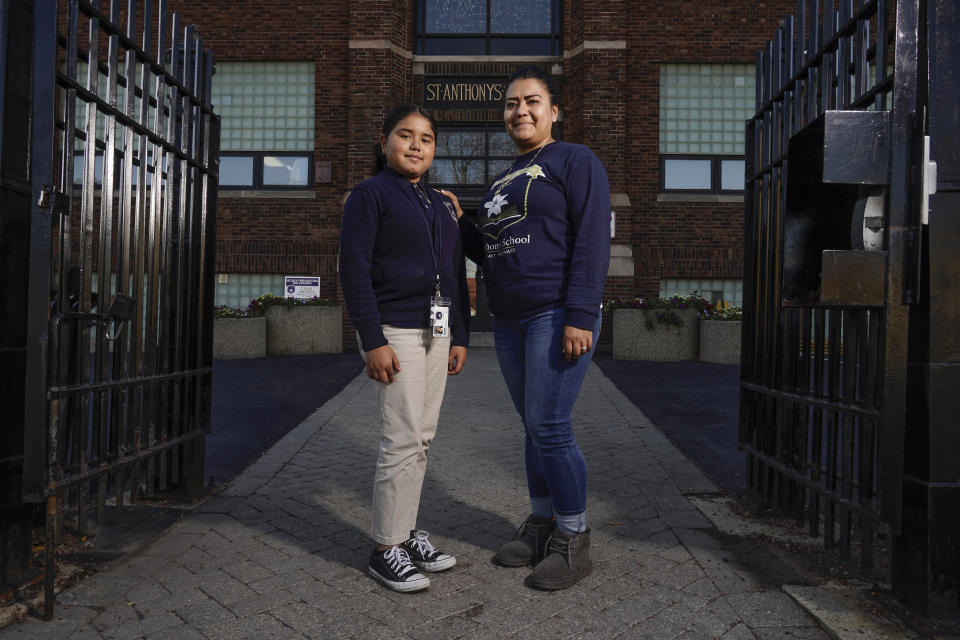 Lorena Ramirez poses with her daughter Citlalli outside St. Anthony School Thursday, Oct. 20, 2022, in Milwaukee. School choice allows taxpayer money to pay for private school tuition instead of only financing public schools. “It’s a huge difference because it’s a support in faith and in values,” said Ramirez, whose four children attend St. Anthony, walking distance from home on Milwaukee's south side. (AP Photo/Morry Gash)