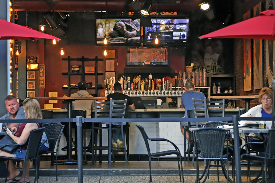 FILE - In this Sunday, June 28, 2020 file photo, people gather at a bar in Pittsburgh. In July 2020, authorities are closing drinking establishments in some parts of the U.S. to stem the surge of COVID-19 infections — a move backed by sound science about risk factors that go beyond wearing or not wearing masks. In the words of one study, it comes down to the danger of “heavy breathing in close proximity." (AP Photo/Gene J. Puskar)