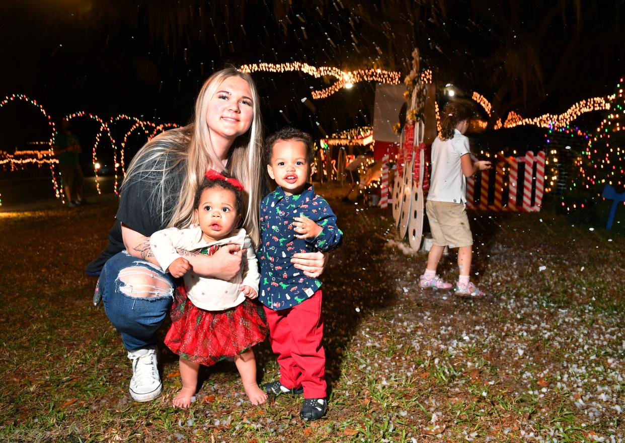 A'Lea Smith, with her kids, Josie, 1, and Jet, 2, check out a Christmas display, complete with falling "snow", at a home in Sarasota. 