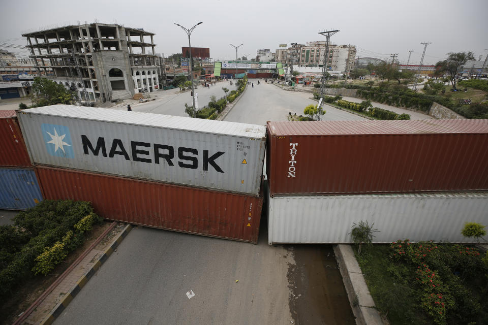 Authorities place shipping containers to block a road leading to the capital as a security measure on the possible anti-France protest march by a banned radical Islamists Tehreek-e-Labaik Pakistan party, in Rawalpindi, Pakistan, Tuesday, April 20, 2021. Pakistan's Parliament is expected to consider a resolution on Tuesday about whether the French envoy should be expelled over the publication of controversial cartoons depicting Islam's Prophet, testing whether the government gives in to threats from radical Islamists. (AP Photo/Anjum Naveed)