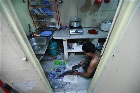 A Rohingya man cuts a fish at his rented house in Cheras Baru, Kuala Lumpur March 2, 2014. REUTERS/Samsul Said