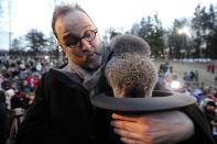 PUNXSUTAWNEY, PA - FEBRUARY 2: Groundhog handler Ben Hughes watches Punxsutawney Phil after he did not see his shadow predicting an early spring during the 125th annual Groundhog Day festivities on February 2, 2011 in Punxsutawney, Pennsylvania. Groundhog Day is a popular tradition in the United States and Canada. A smaller than usual crowd this year of less than 15,000 people spent a night of revelry awaiting the sunrise and the groundhog's exit from his winter den. If Punxsutawney Phil sees his shadow he regards it as an omen of six more weeks of bad weather and returns to his den. Early spring arrives if he does not see his shadow causing Phil to remain above ground. (Photo by Jeff Swensen/Getty Images)