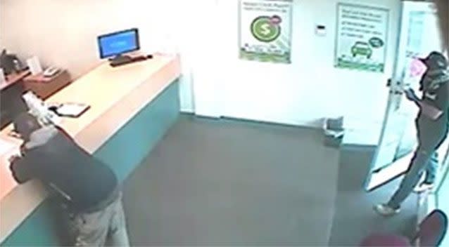 A thief jumps the counter and demands cash from a money lending store, then helps himself to money in the safe. Pictures: Victoria Police