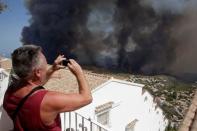 A tourist takes pictures of a wildfire in Benitatxell near Alicante, Spain September 5, 2016. REUTERS/Heino Kalis