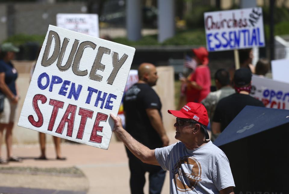 In this April 20, 2020, photo, protesters rally at the state Capitol to 're-open' Arizona against the governor's stay-at-home order due to the coronavirus in Phoenix. (AP Photo/Ross D. Franklin)