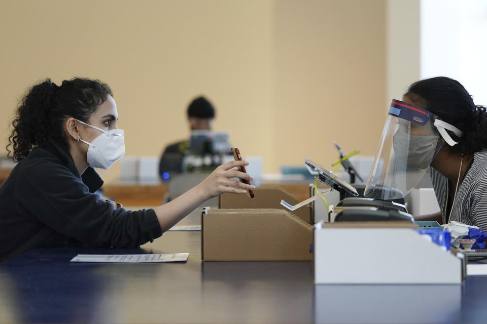 Riya Madan, left, verifies her information with poll worker Sharri Nurein, right, as she cast her ballot inside the Frederick R. Weisman Art Museum at the University of Minnesota in Minneapolis on Tuesday, Aug. 11, 2020. (Anthony Souffle/Star Tribune via AP)