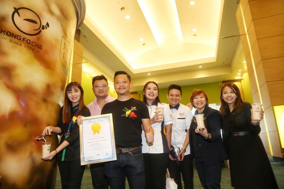 Kong Fo Cha Malaysia operations manager Chua Li Peng (far left) dispensing a cup of milk tea with OnOn App founder Sanny Chin (left, in black), Malaysia Book of Records representatives, and TeaFest organisers. — Picture by Choo Choy May