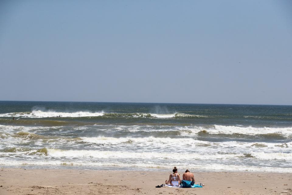 Two people sit on the beach on North Padre Island on Easter Sunday, April 12, 2020.