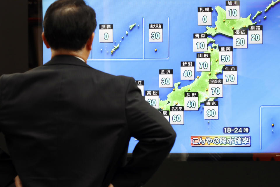 A man watches a public TV of weather forecast in Tokyo Friday, Oct. 11, 2019. Japan's weather agency is warning a powerful typhoon may bring torrential rains to central Japan over the weekend. (AP Photo/Eugene Hoshiko)