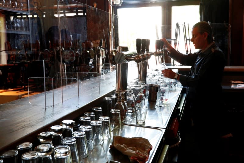 A waiter pours a beer in front of a protective plexiglass screen amid the coronavirus disease (COVID-19) outbreak in Brussels