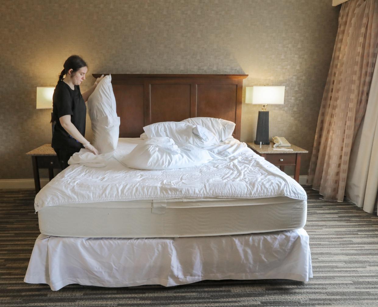 Sheraton Suites suite attendant Jessica Tidwell changes the linens in a guest room on Friday. The 209-room hotel in Cuyahoga Falls is sold out for both Sunday and Monday nights.