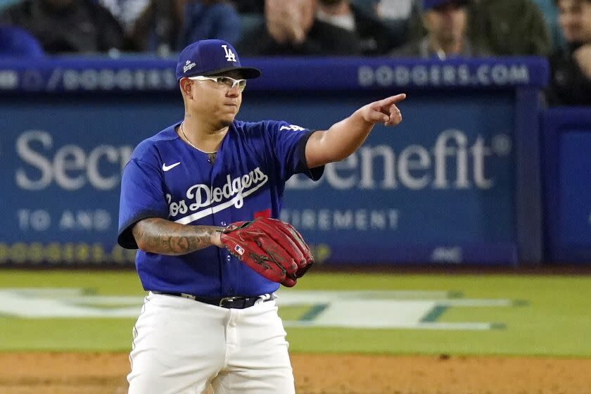 Los Angeles Dodgers starting pitcher Julio Urias gestures toward shortstop Miguel Rojas.