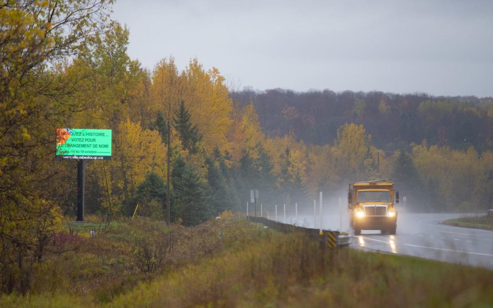 A truck passes a sign reading "Make History And Vote For A Name Change" as residents vote for a new town name in Asbestos - Christinne Muschi /Bloomberg