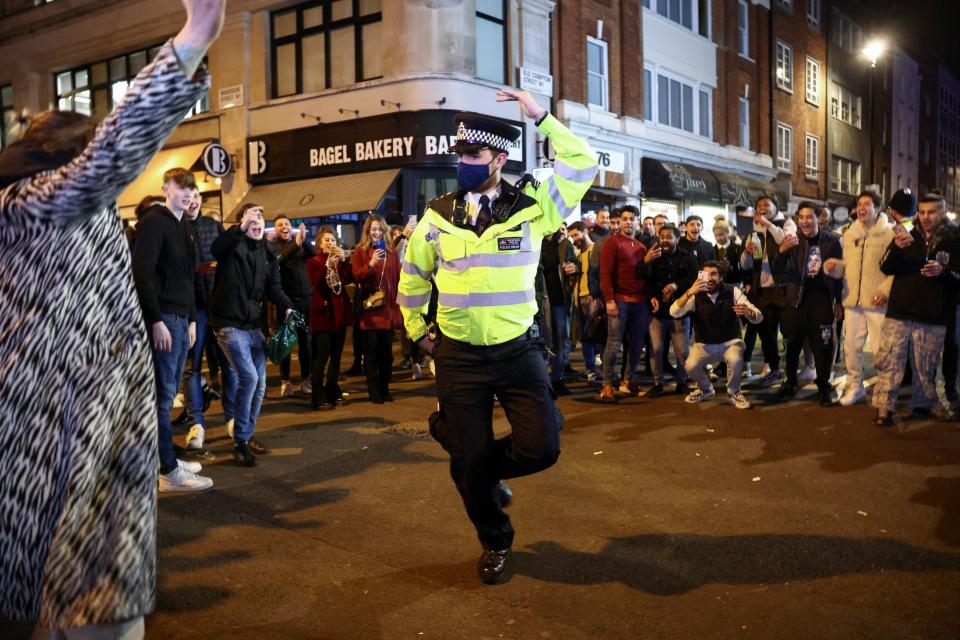 A policeman dances with people partying along a street in SohoREUTERS