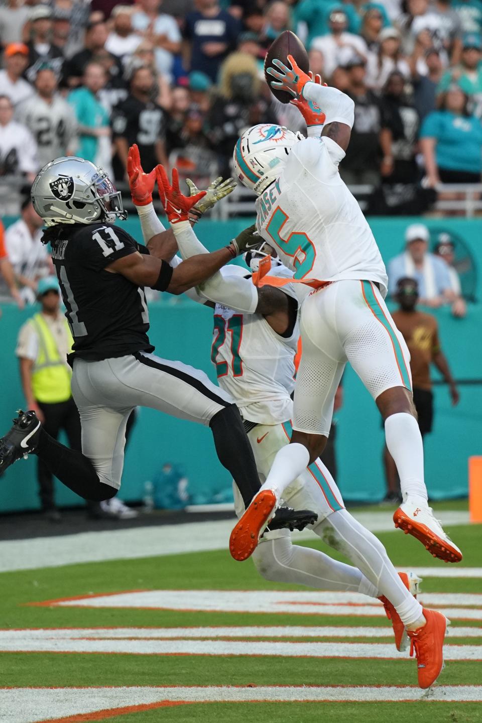 Miami Dolphins cornerback Jalen Ramsey (5) intercepts a pass intended for Las Vegas Raiders wide receiver Tre Tucker (11) late in the game as Miami Dolphins safety DeShon Elliott (21) closes in during the fourth quarter of an NFL game at Hard Rock Stadium in Miami Gardens, Nov. 19, 2023.