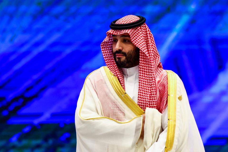 Saudi Crown Prince Mohammed bin Salman, in Saudi dress with white robe trimmed in gold and red-and-white checkered dishdasha. attends the 