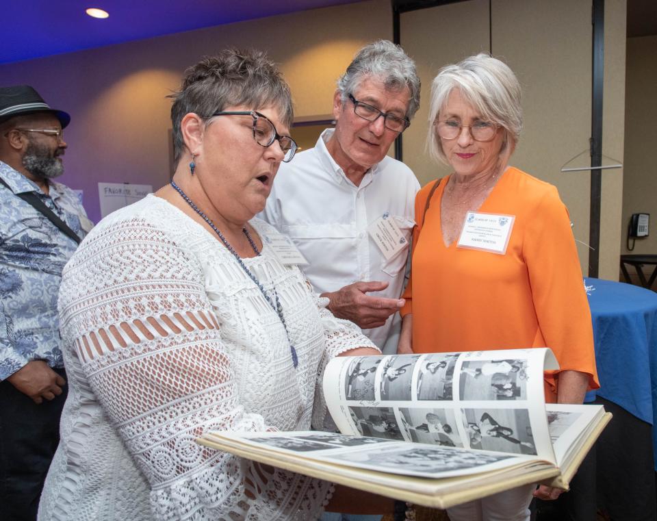 From left, Tonya Bell Watkins, Chuck Norton, and Sandy Norton check out a yearbook during Booker T. Washington High School class of 1973’s 50th reunion at the Hilton Garden Inn in Pensacola on Friday, May 5, 2023.  The Class of ’73 was the first to enter and graduate from the then newly desegregated school.