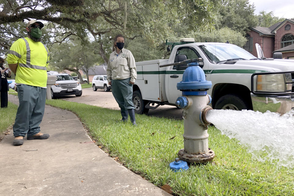 City workers Kristina Watson, right, and Lennie Miner, a maintenance foreman monitor Monday, Sept. 28, 2020, test water flowing out of a hydrant in Lake Jackson, Texas. The city remains under a boil water advisory after a deadly microbe was found to have caused the death of a 6-year-old boy exposed to contaminated water in the city supply. (AP Photo/Jim Mone)