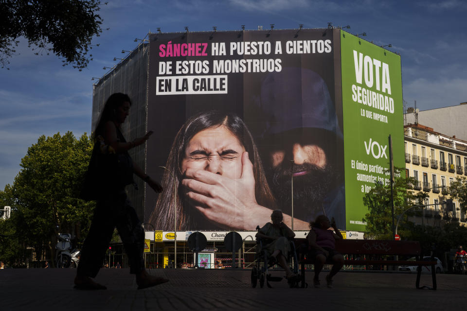 Una mujer pasa junto a un cartel electoral del partido de ultraderecha Vox en un edificio en Madrid, España, el miércoles 12 de julio de 2023. (AP Foto/Manu Fernández)