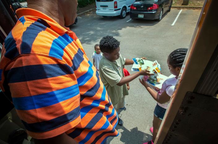 Children check their trays before leaving with a lunch from the CHOW Bus during a stop at Campus Villa Apartments.
JIM DAVIS/FOR THE DNJ