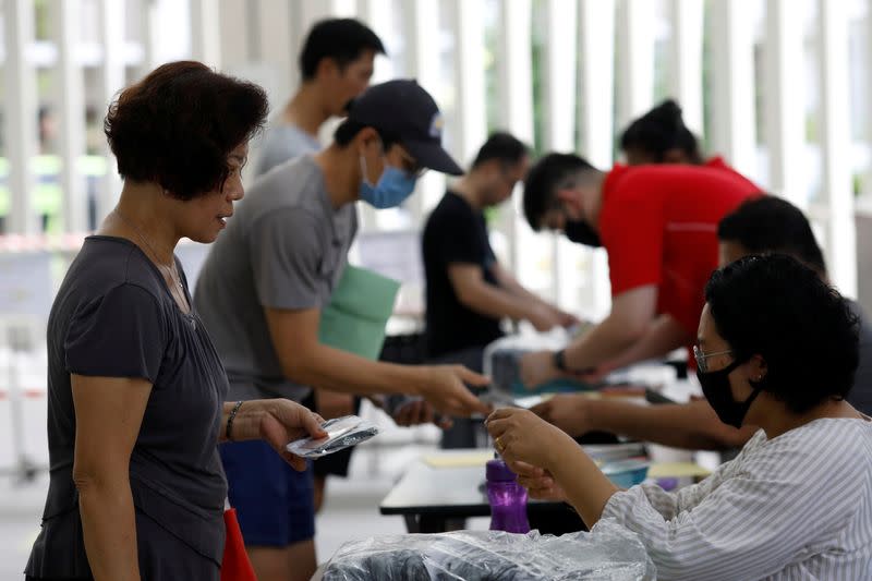 Residents receive free reusable masks distributed by the government at a community center, as stricter measures are announced to combat the outbreak of the coronavirus disease (COVID-19) in Singapore