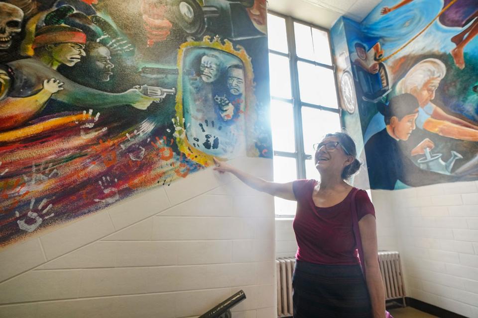 Social work professor Yolanda Padilla smiles while looking at the handprints in the mural at the University of Texas' School of Social Work.