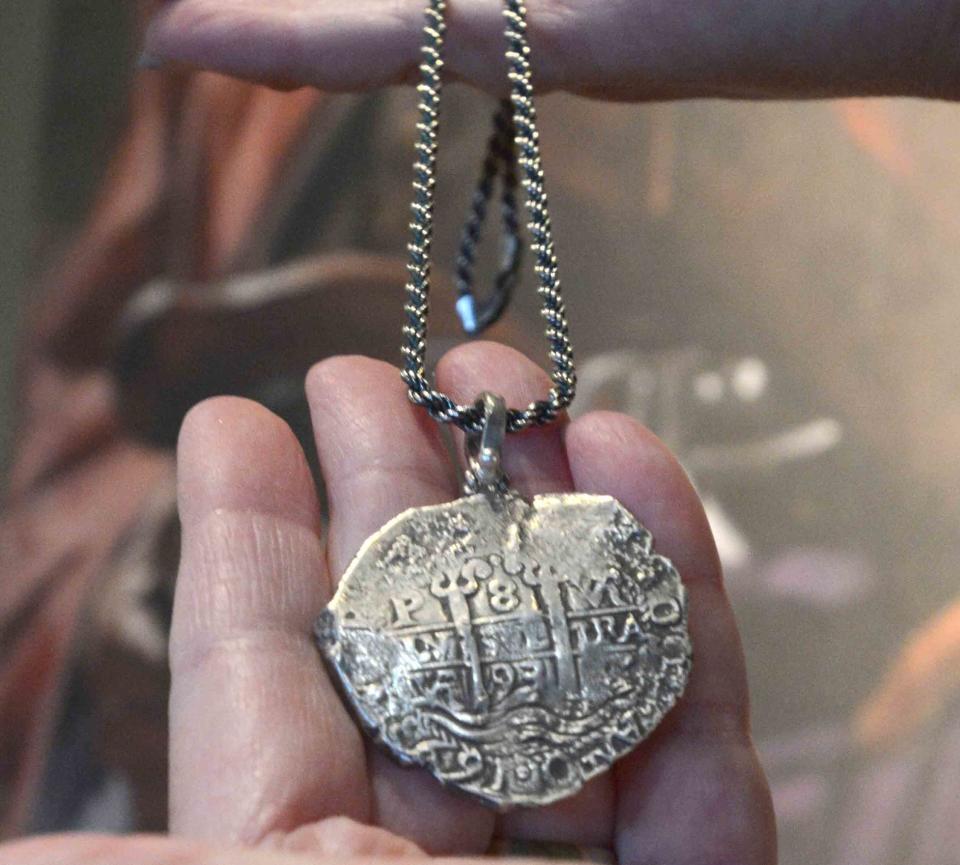 Meredith Katz holds a sterling silver replica of a 1693 coin made into a necklace at the Whydah Pirate Museum. The replica necklace is part of the prize put together by the West Yarmouth museum for the person who solved The Brewster Boys poem riddle by Dec. 31.