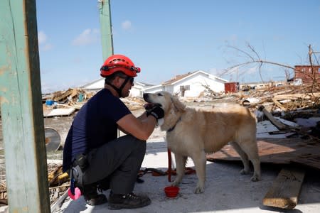 A member of the Canadian Burnaby Firefighters Search & Rescue Task Force pampers his dog during a search for the dead operation in the destroyed the Mudd neighbourhood after Hurricane Dorian hit the Abaco Islands in Marsh Harbour