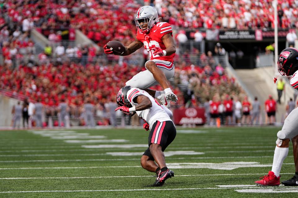 Sep 16, 2023; Columbus, Ohio, USA; Ohio State Buckeyes running back TreVeyon Henderson (32) leaps over Western Kentucky Hilltoppers defensive back Anthony Johnson Jr. (4) during the first half of the NCAA football game at Ohio Stadium.