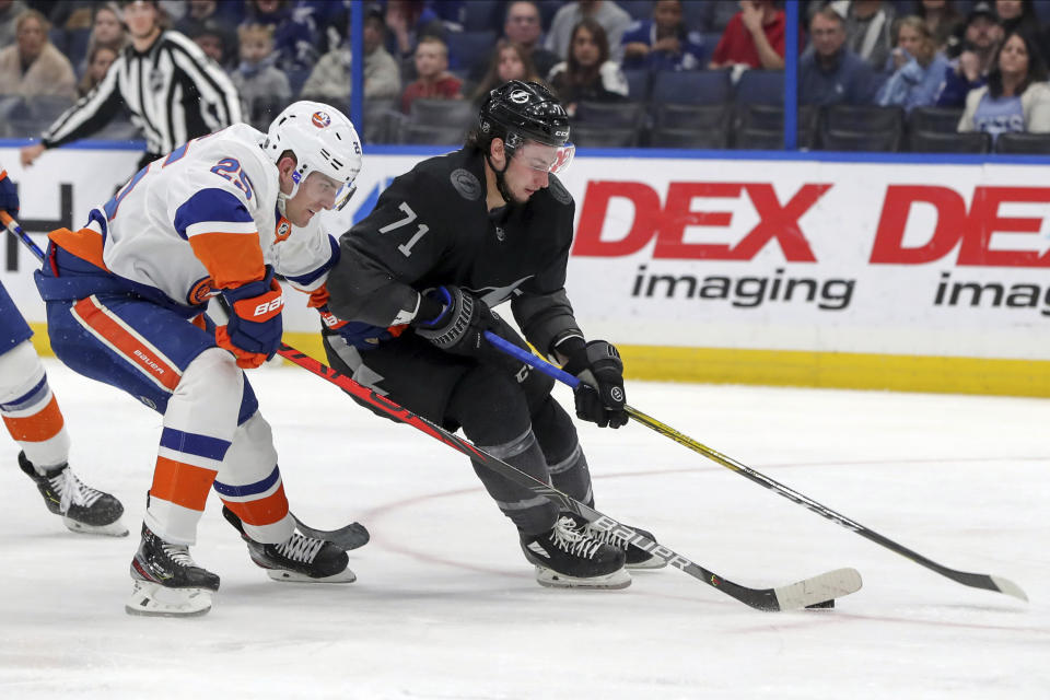 Tampa Bay Lightning's Anthony Cirelli avoids a check from New York Islanders' Devon Toews during the second period of an NHL hockey game Saturday, Feb. 8, 2020, in Tampa, Fla. (AP Photo/Mike Carlson)