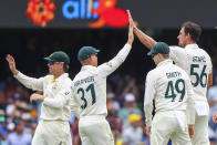 Australia's Mitchell Starc, right, is congratulated by teammates after taking the wicket of England's Jos Buttler during day one of the first Ashes cricket test at the Gabba in Brisbane, Australia, Wednesday, Dec. 8, 2021. (AP Photo/Tertius Pickard)