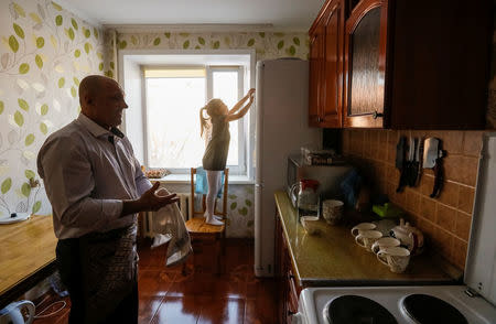 Petr Smotrich, a furnace operator at Aksu Ferroalloys Plant since 1978, wipes his hands in the kitchen, as his eight-year-old granddaughter Dana, plays nearby at his apartment in the town of Aksu, north-eastern Kazakhstan, February 22, 2018. REUTERS/Shamil Zhumatov/Files