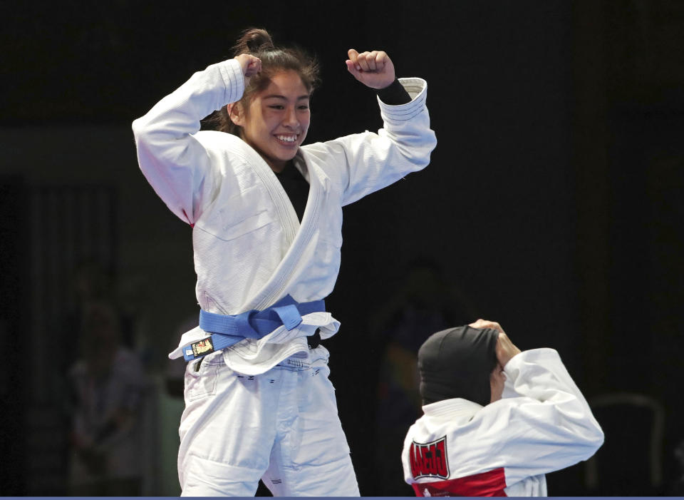 Jessa Khan of Cambodia, left, reacts after defeating Mahra Alhinaai of United Arab Emirates, right, during their newaza women's - 49 kilogram jujitsu final at the 18th Asian Games in Jakarta, Indonesia, Friday, Aug. 24, 2018. (AP Photo/Firdia Lisnawati)