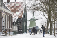 People take a stroll at the Zaans Museum in Zaandam, Netherlands, Sunday, Feb. 7, 2021. Snow and strong winds pounded The Netherlands, with more snow and cold temperatures expected in the days ahead. (AP Photo/Peter Dejong)