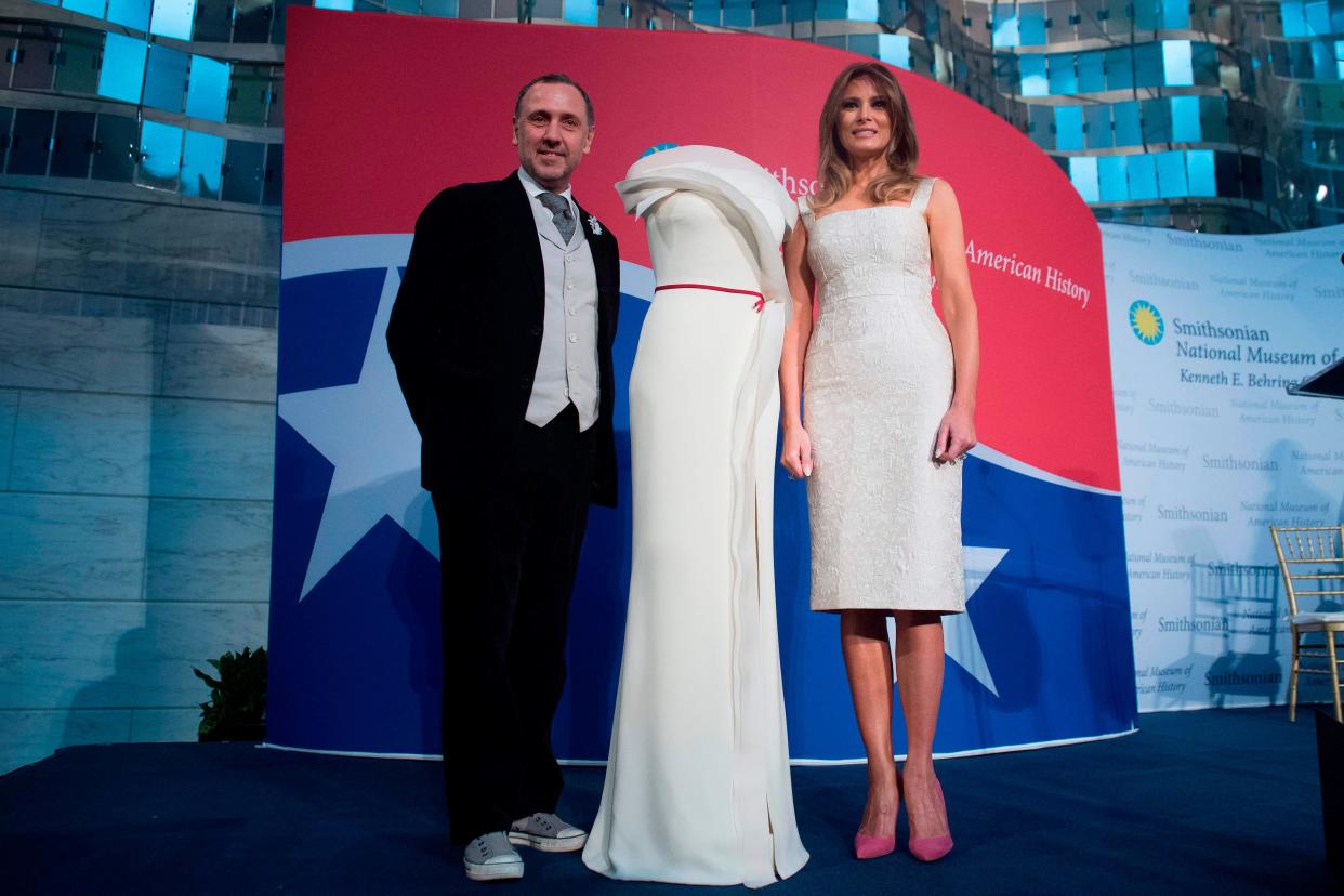 First lady Melania Trump stands alongside the gown she wore to the 2017 inaugural balls, and the gown's designer, Herve Pierre, as she donates the dress to the Smithsonian's First Ladies Collection at the Smithsonian National Museum of American History in Washington, D.C, on Oct. 20, 2017
