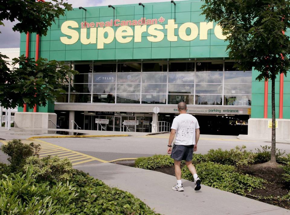 Un homme marche devant le Real Canadian Superstore de Coquitlam, en Colombie-Britannique