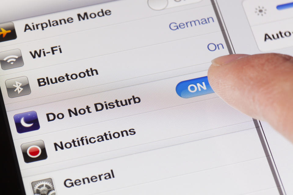 A close-up shot of a smartphone settings screen showing options for Airplane Mode, Wi-Fi, Bluetooth, and Do Not Disturb, with a finger toggling "Do Not Disturb" on