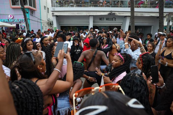 Keandre Reese, center, dances in a crowd of Spring Breakers front of Wet Willies on Sunday, March 19, 2023, on Ocean Drive in Miami.