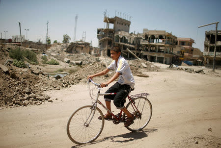 An Iraqi boy passes destroyed buildings in western Mosul, Iraq August 5, 2017. REUTERS/Suhaib Salem
