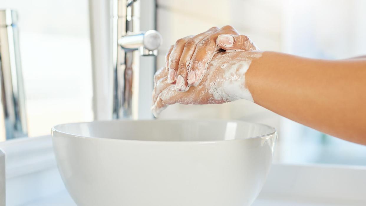 Cropped shot of an unrecognizable young woman washing her hands in the bathroom basin at home.