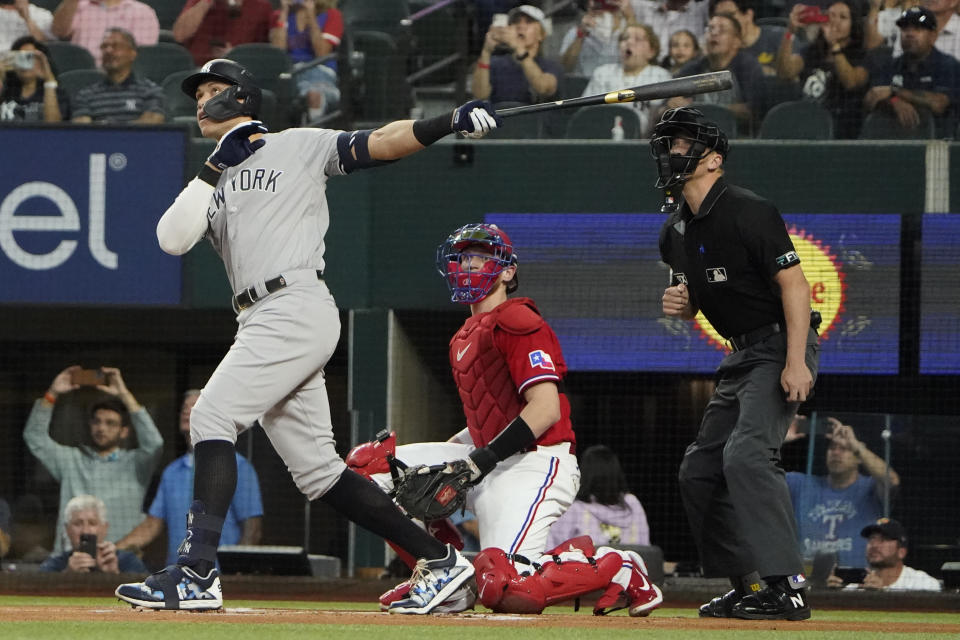 New York Yankees' Aaron Judge, left, hits a solo home, his 62nd of the season, in front of Texas Rangers catcher Sam Huff and home plate umpire Chris Segal during the first inning in the second baseball game of a doubleheader in Arlington, Texas, Tuesday, Oct. 4, 2022. With the home run, Judge set the AL record for home runs in a season, passing Roger Maris. (AP Photo/LM Otero)