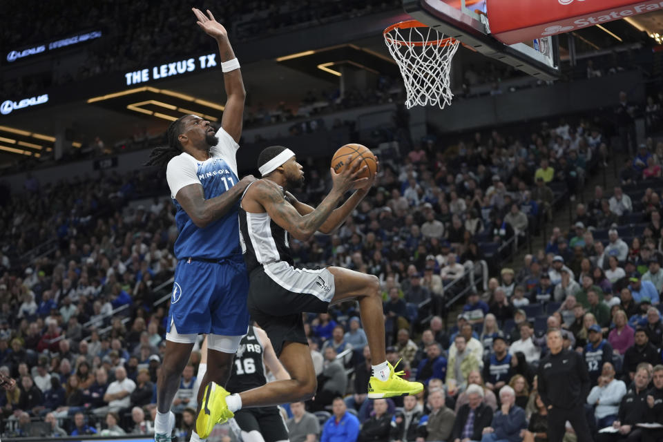 San Antonio Spurs guard Blake Wesley, right, goes up for a shot as Minnesota Timberwolves center Naz Reid defends during the first half of an NBA basketball game Tuesday, Feb. 27, 2024, in Minneapolis. (AP Photo/Abbie Parr)