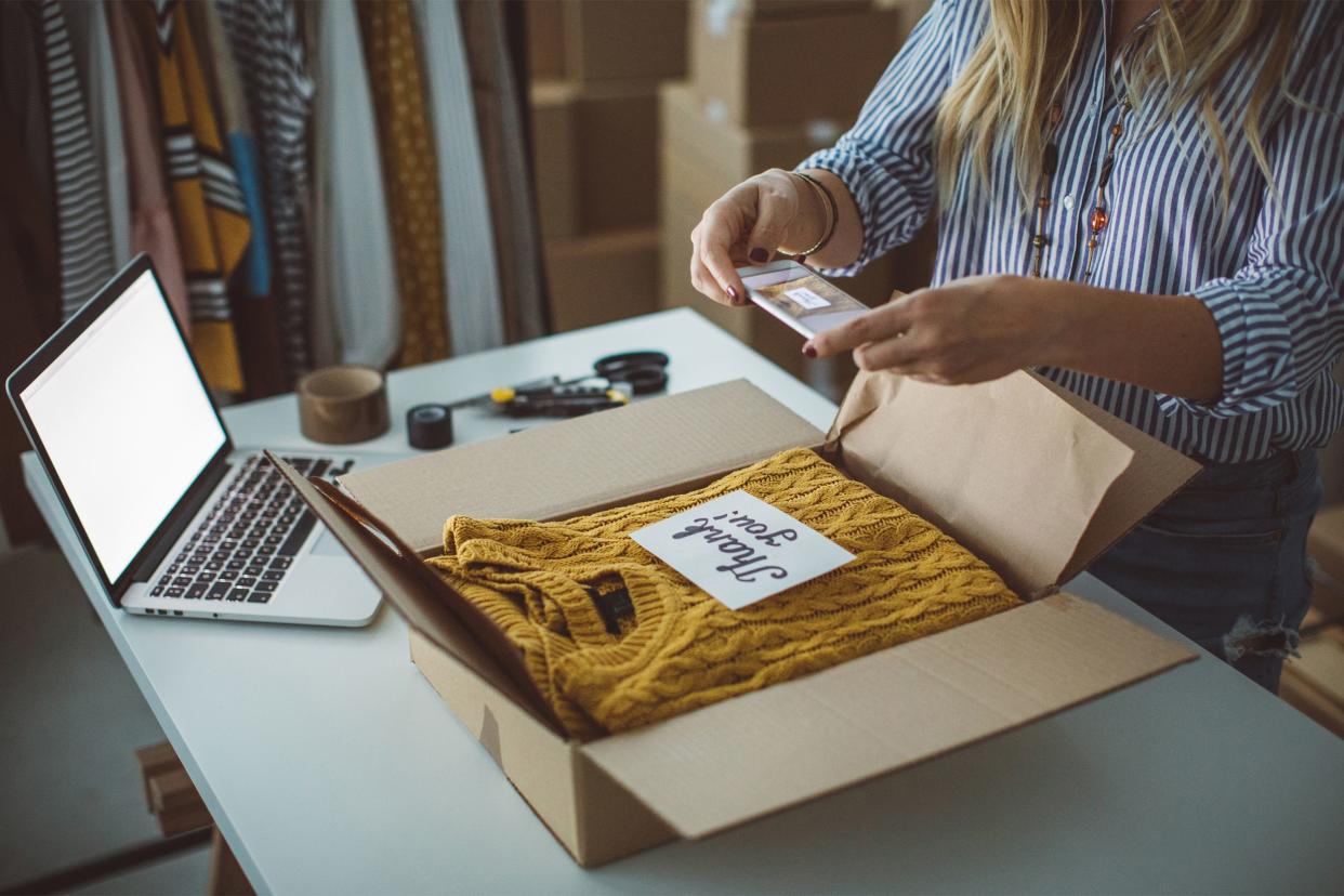 Woman taking pictures of clothing in a box to sell